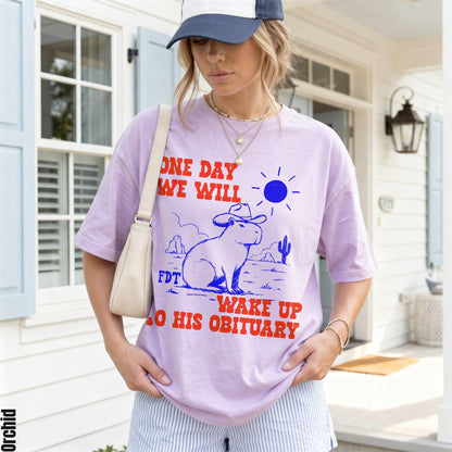 Light purple t-shirt with red text and blue graphic of a capybara in a desert.
