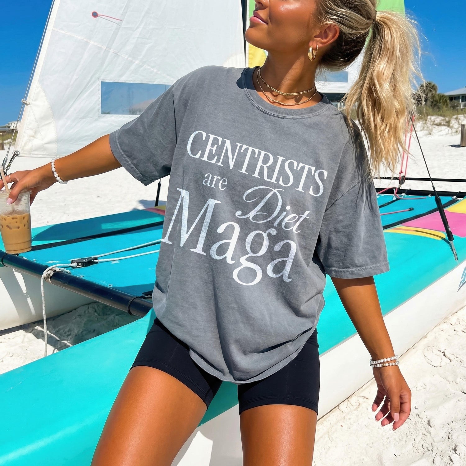 Gray t-shirt with &amp;quot;Centrists are Diet Maga&amp;quot; text, woman holding a drink on a beach.
