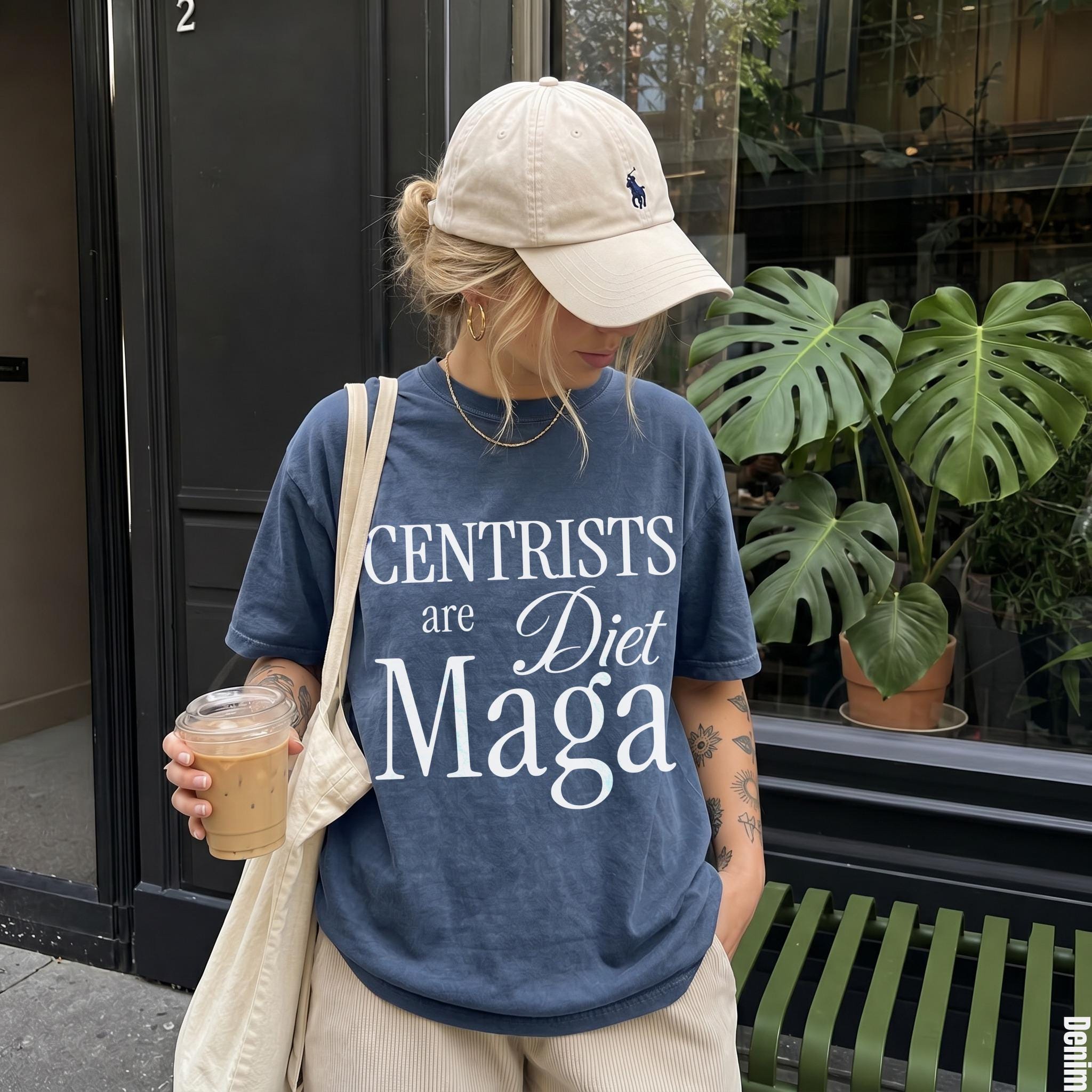 Woman wearing a dark blue t-shirt with &amp;quot;Centrists are Diet Maga&amp;quot; text, holding a coffee.