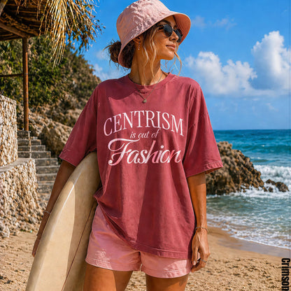 Woman on beach holds surfboard wearing pink bucket hat and shirt with text.