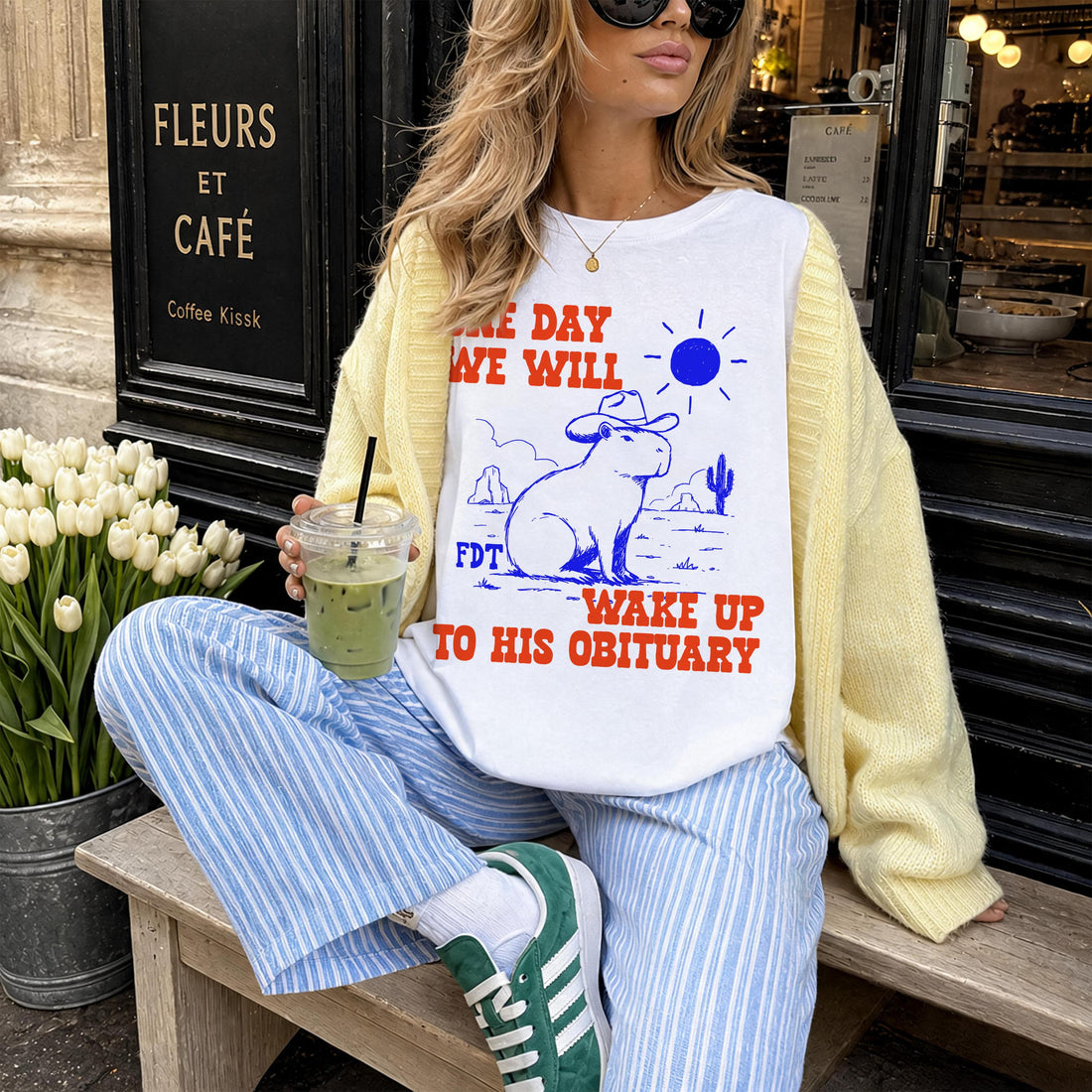 White t-shirt with capybara graphic and text &amp;quot;ONE DAY WE WILL WAKE UP TO HIS OBITUARY&amp;quot;.
