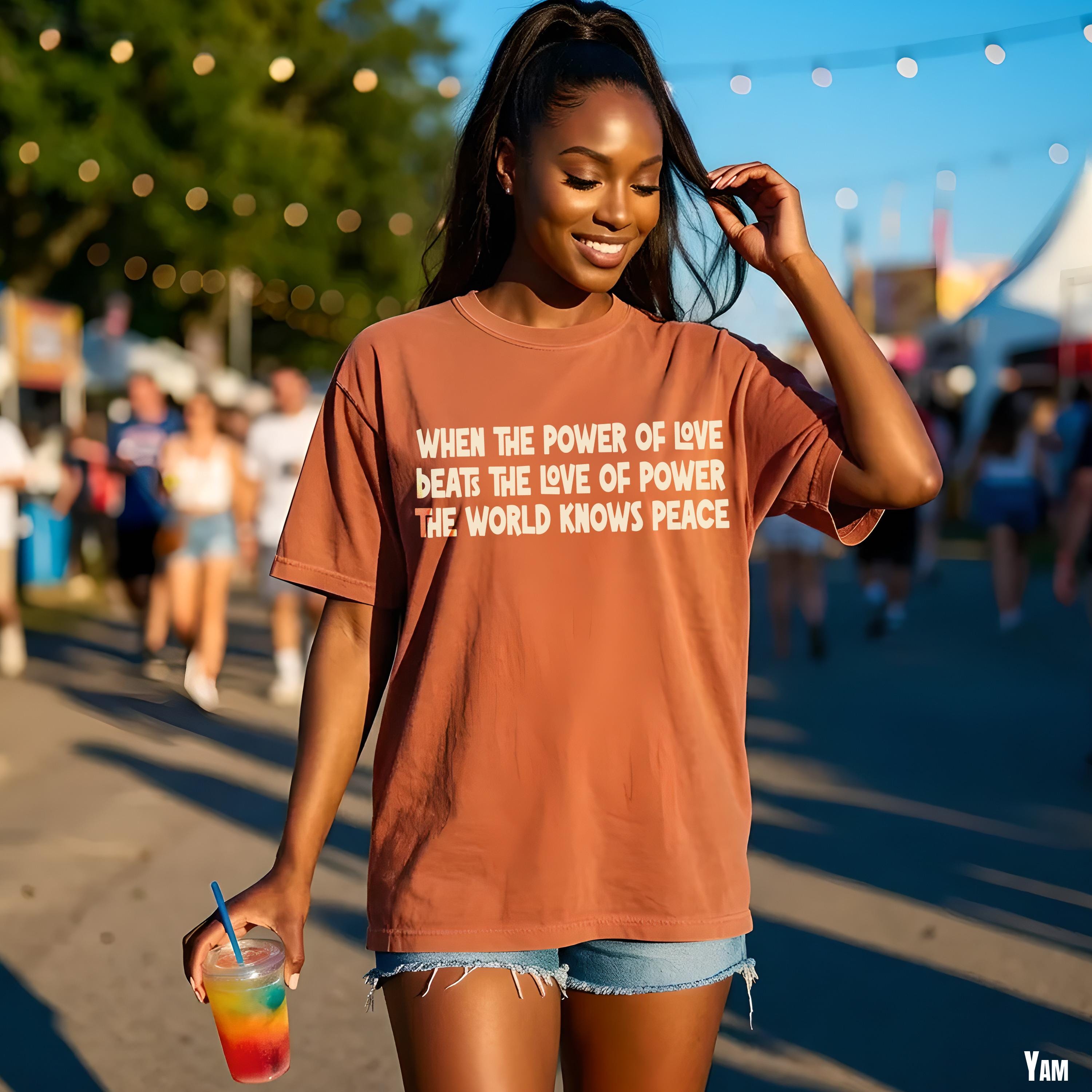 Woman wears rust-colored t-shirt with white text: &amp;quot;When the power of love beats the love of power the world knows peace.&amp;quot;