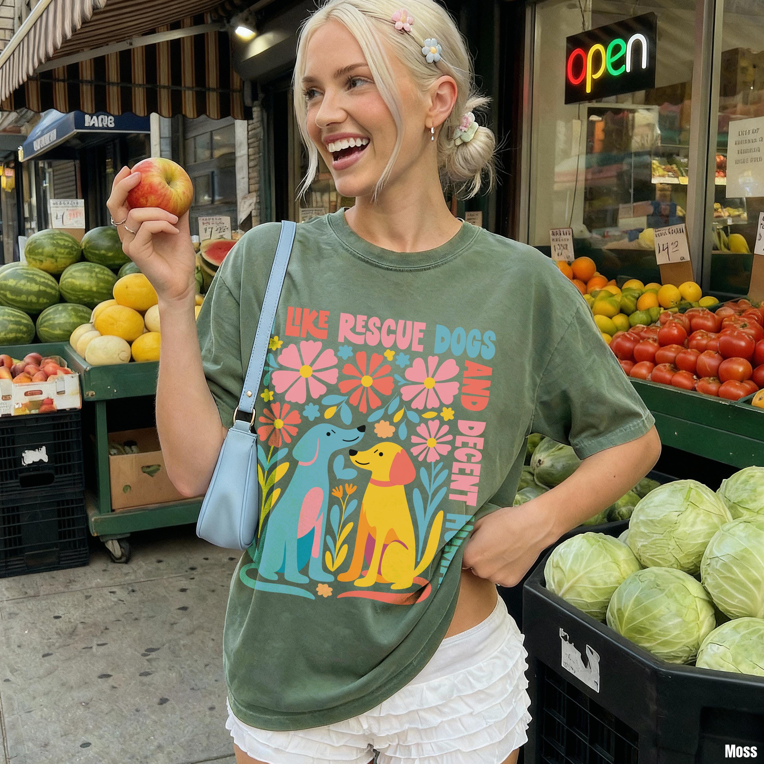 Green t-shirt with &amp;quot;Like Rescue Dogs, Be Decent&amp;quot; text and colorful dog graphics.