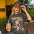 Woman in cowboy hat holding coffee, wearing t-shirt with "Pumpkin Spice F*** Ice" graphic.