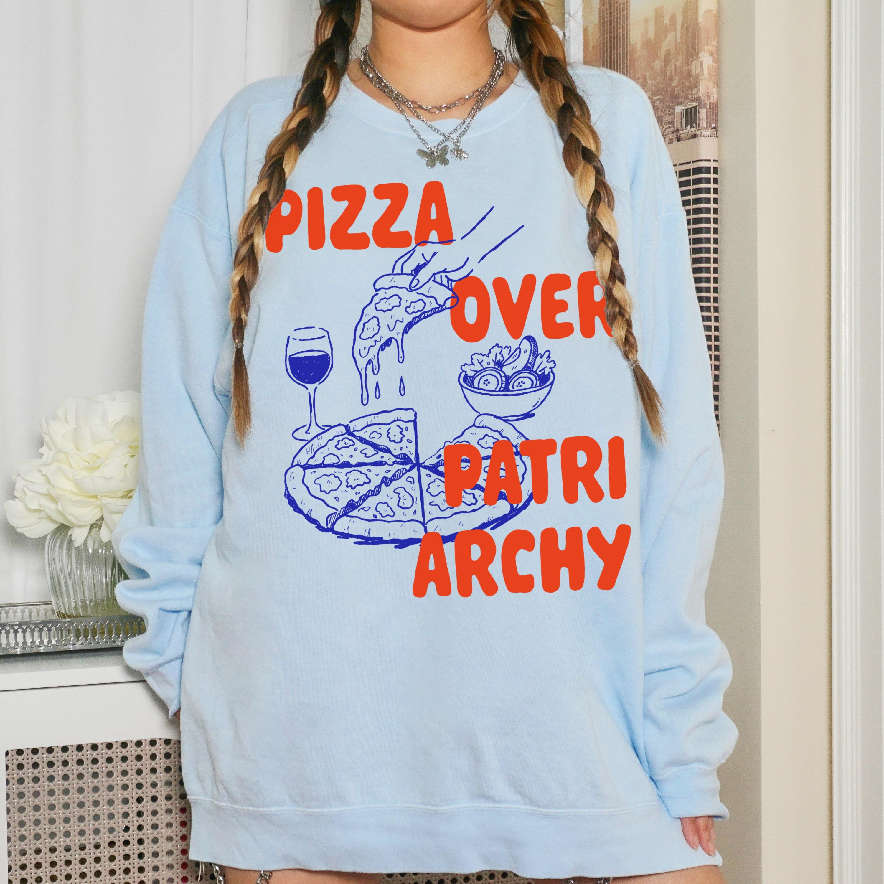 Light blue sweatshirt with orange &amp;quot;Pizza Over Patriarchy&amp;quot; graphic featuring pizza slice and salad.