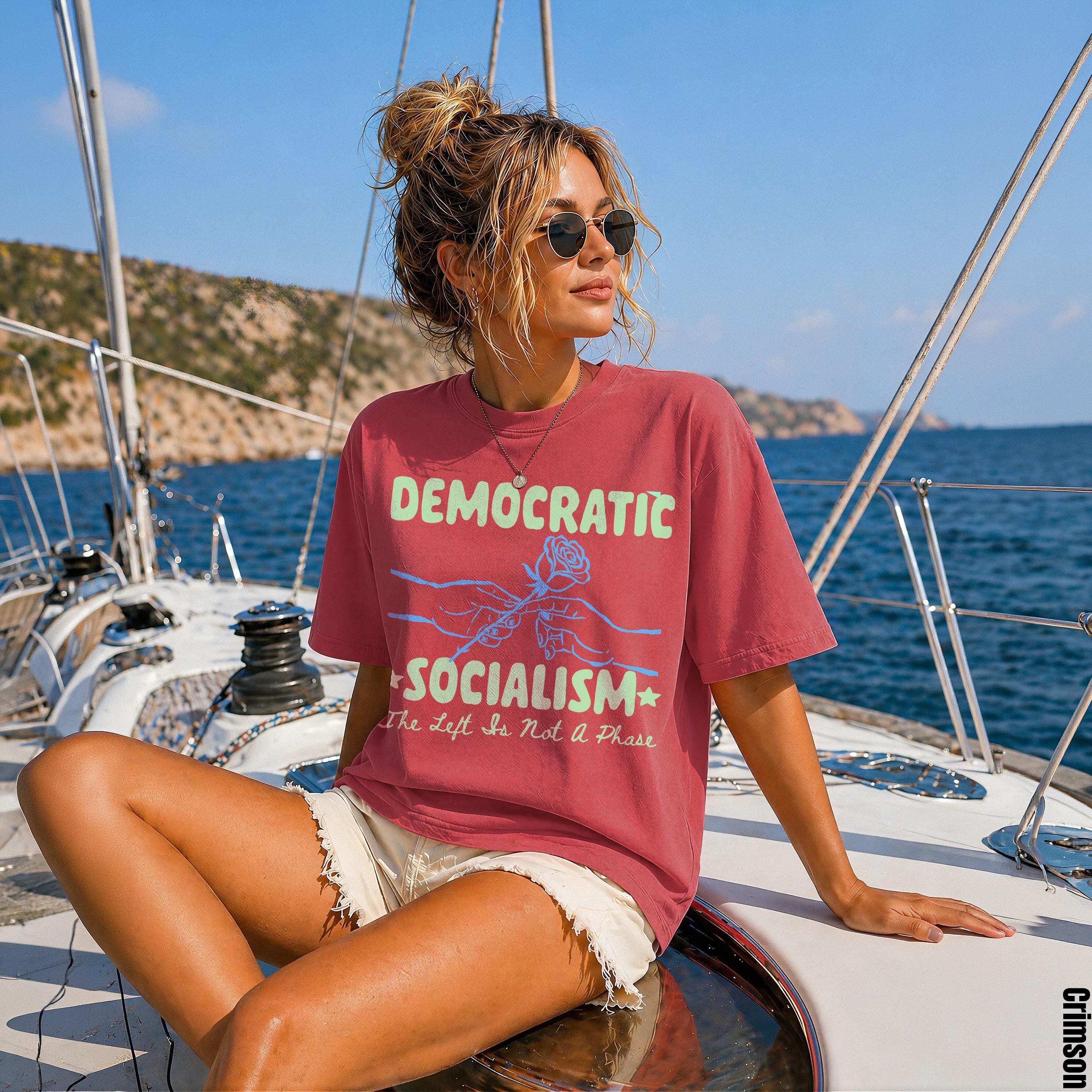 Woman on a sailboat wearing a red t-shirt with &amp;quot;Democratic Socialism&amp;quot; graphic.