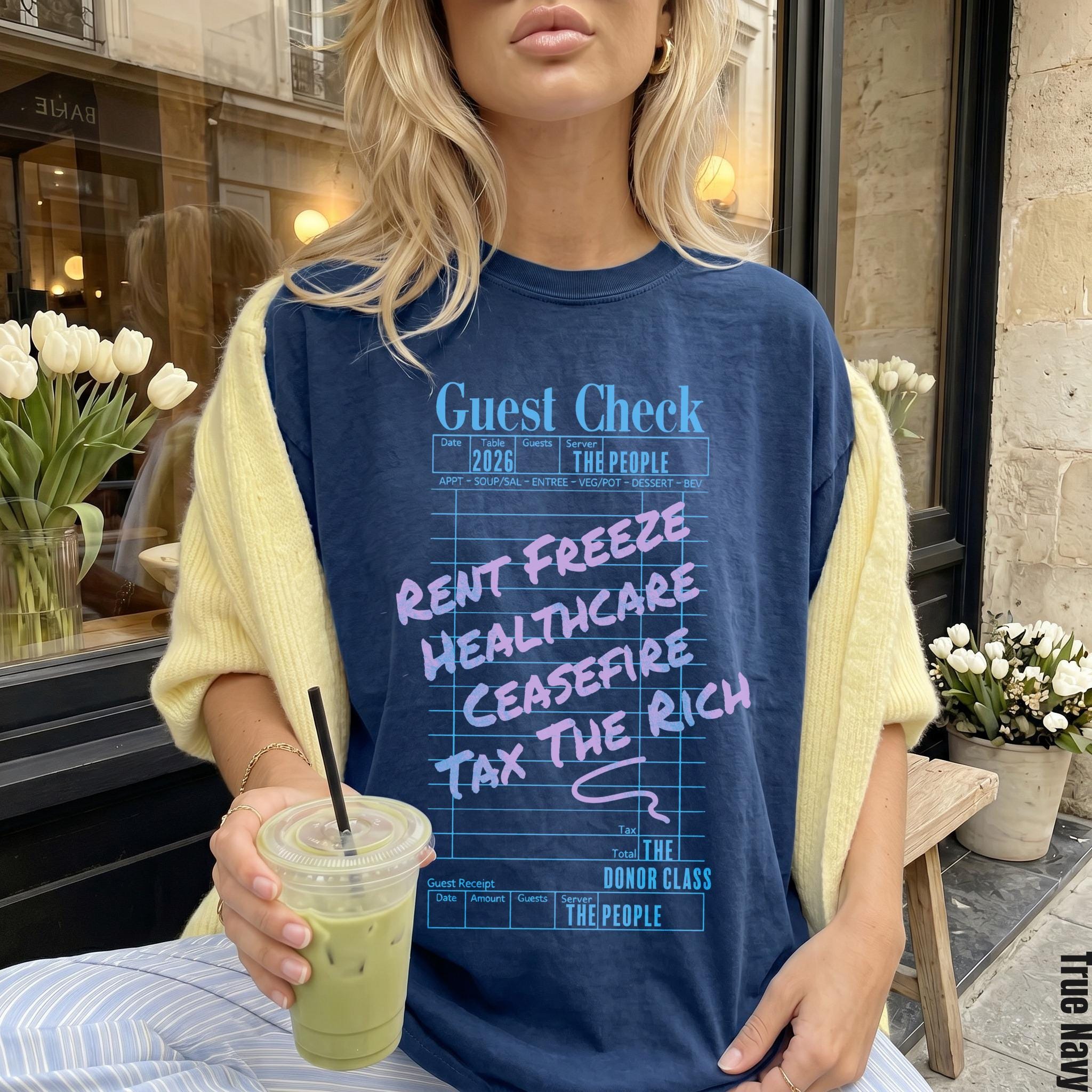 Navy t-shirt with blue and pink text listing &amp;quot;Rent Freeze, Healthcare, Ceasefire, Tax The Rich&amp;quot;.