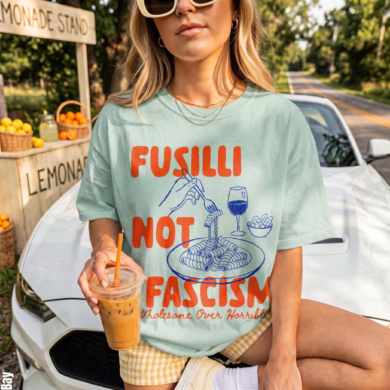 Light blue t-shirt with &amp;quot;Fusilli Not Fascism&amp;quot; graphic over a white car.