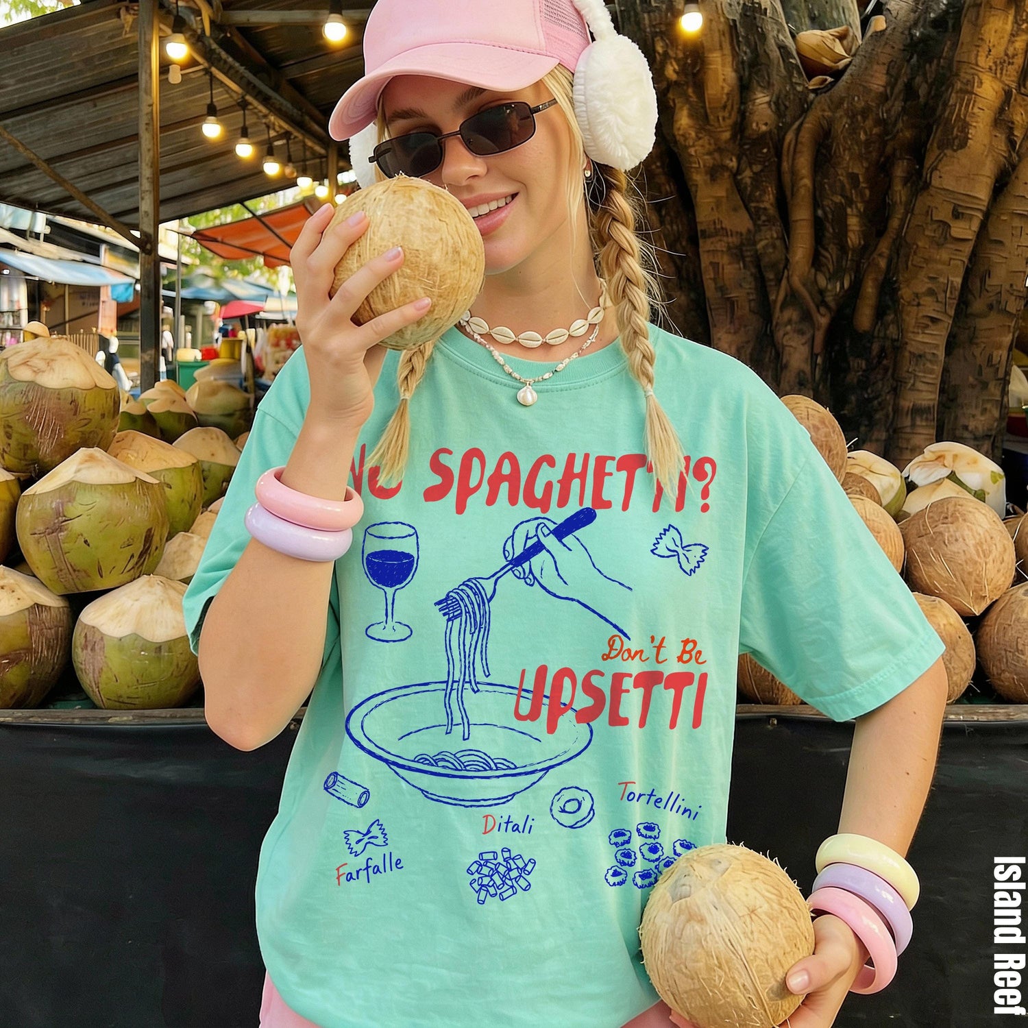 Woman in a pastel green t-shirt holding coconuts with pasta graphics; &amp;quot;Island Reef&amp;quot; text.
