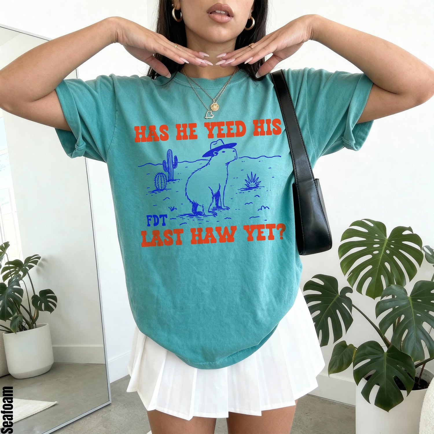 Teal t-shirt with graphic of capybara wearing hat and cactus, text &amp;quot;HAS HE YEED HIS LAST HAW YET?&amp;quot;