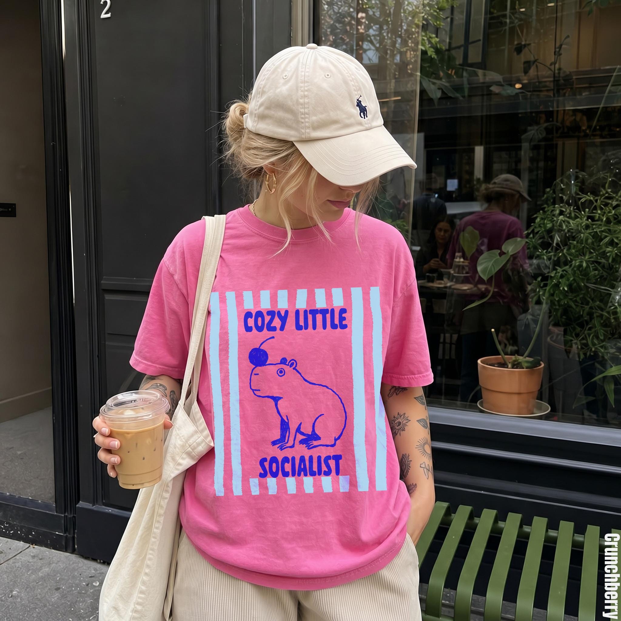 Woman wearing pink t-shirt with capybara and text graphic.