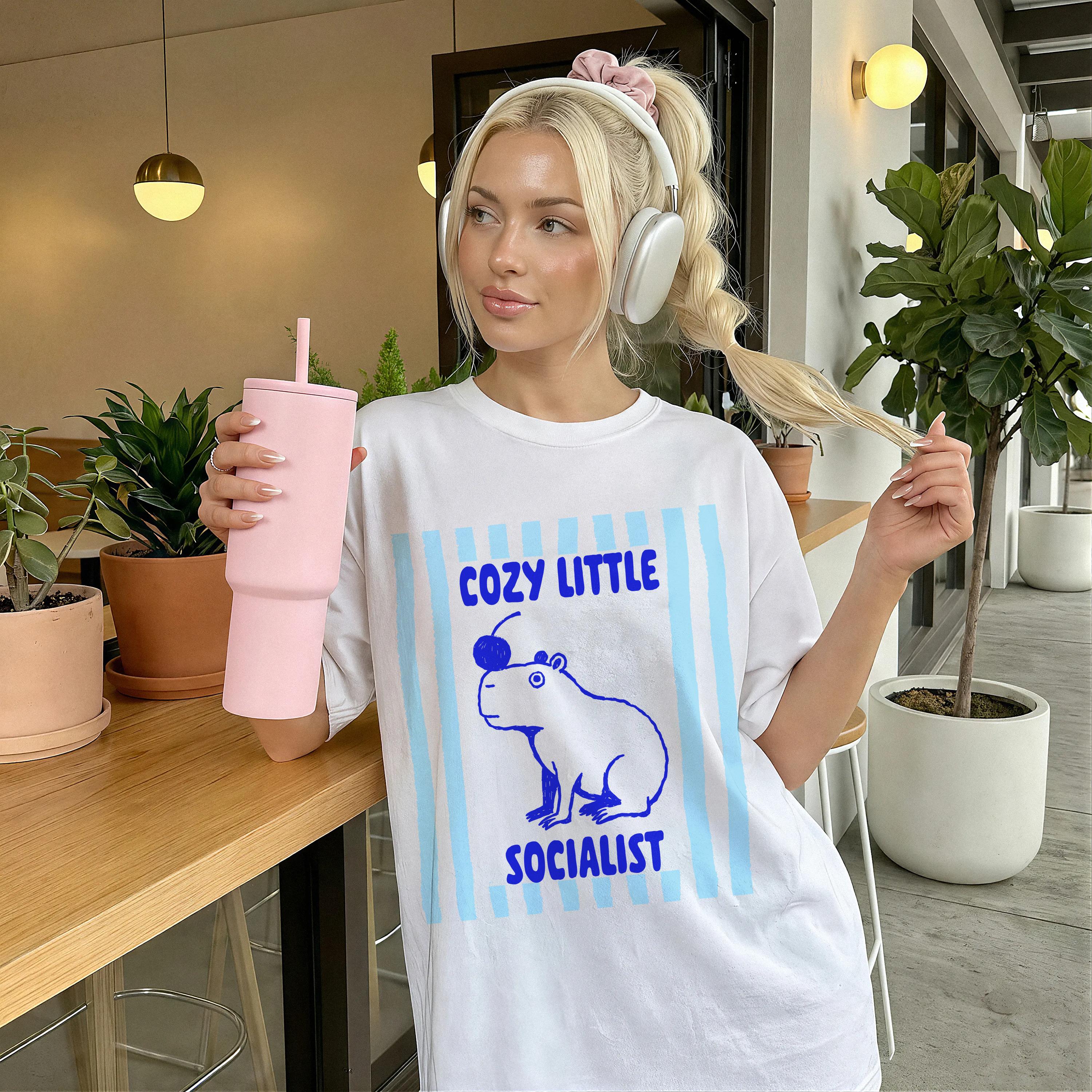 White t-shirt with blue text &amp;quot;COZY LITTLE SOCIALIST&amp;quot; and a capybara graphic.