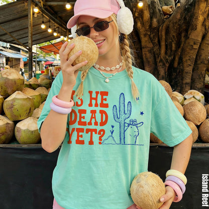 Mint green t-shirt with &amp;quot;IS HE DEAD YET?&amp;quot; text and desert graphic.