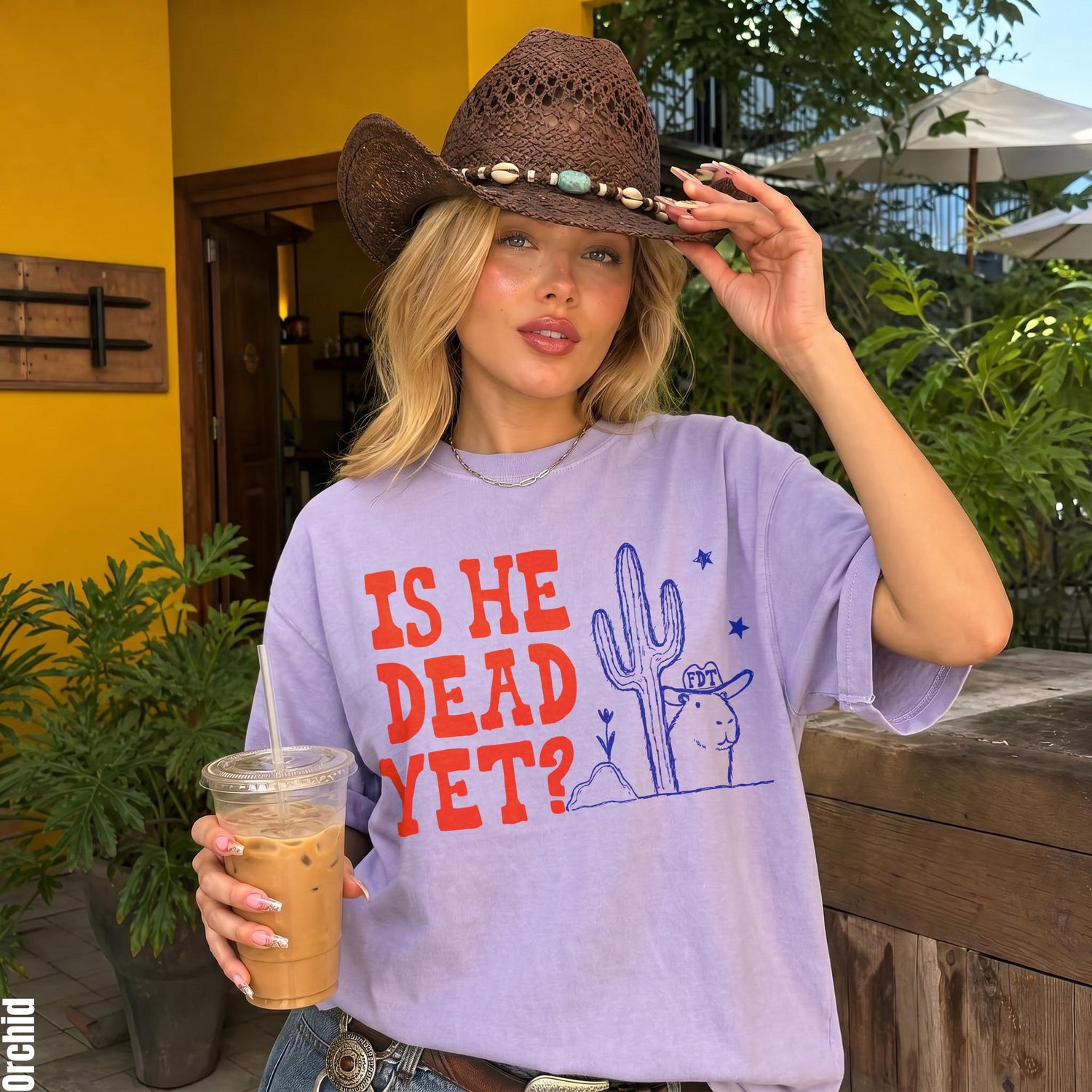Woman wearing lavender t-shirt with &amp;quot;IS HE DEAD YET?&amp;quot; and desert graphic.