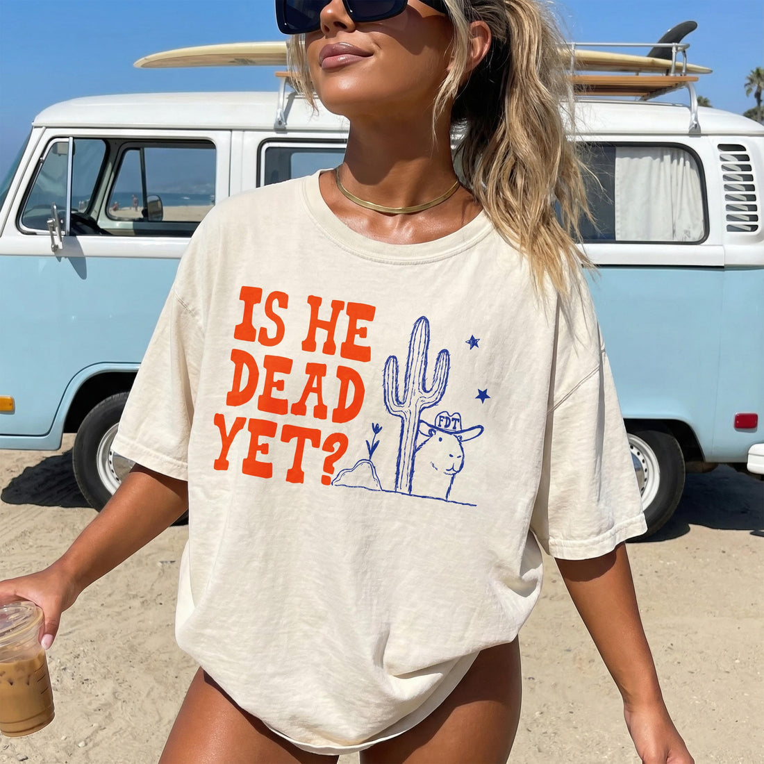 Cream t-shirt with front graphic &amp;quot;IS HE DEAD YET?&amp;quot; and desert illustration.