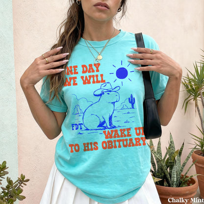 Teal t-shirt with orange text &amp;quot;ONE DAY WE WILL WAKE UP TO HIS OBITUARY.&amp;quot;