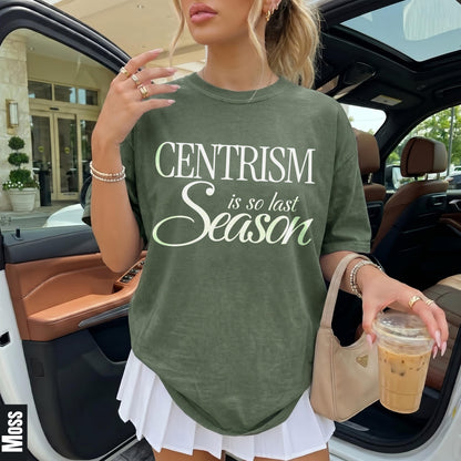 Green t-shirt with &amp;quot;CENTRISM is so last Season&amp;quot; text, holding coffee, wearing white skirt.