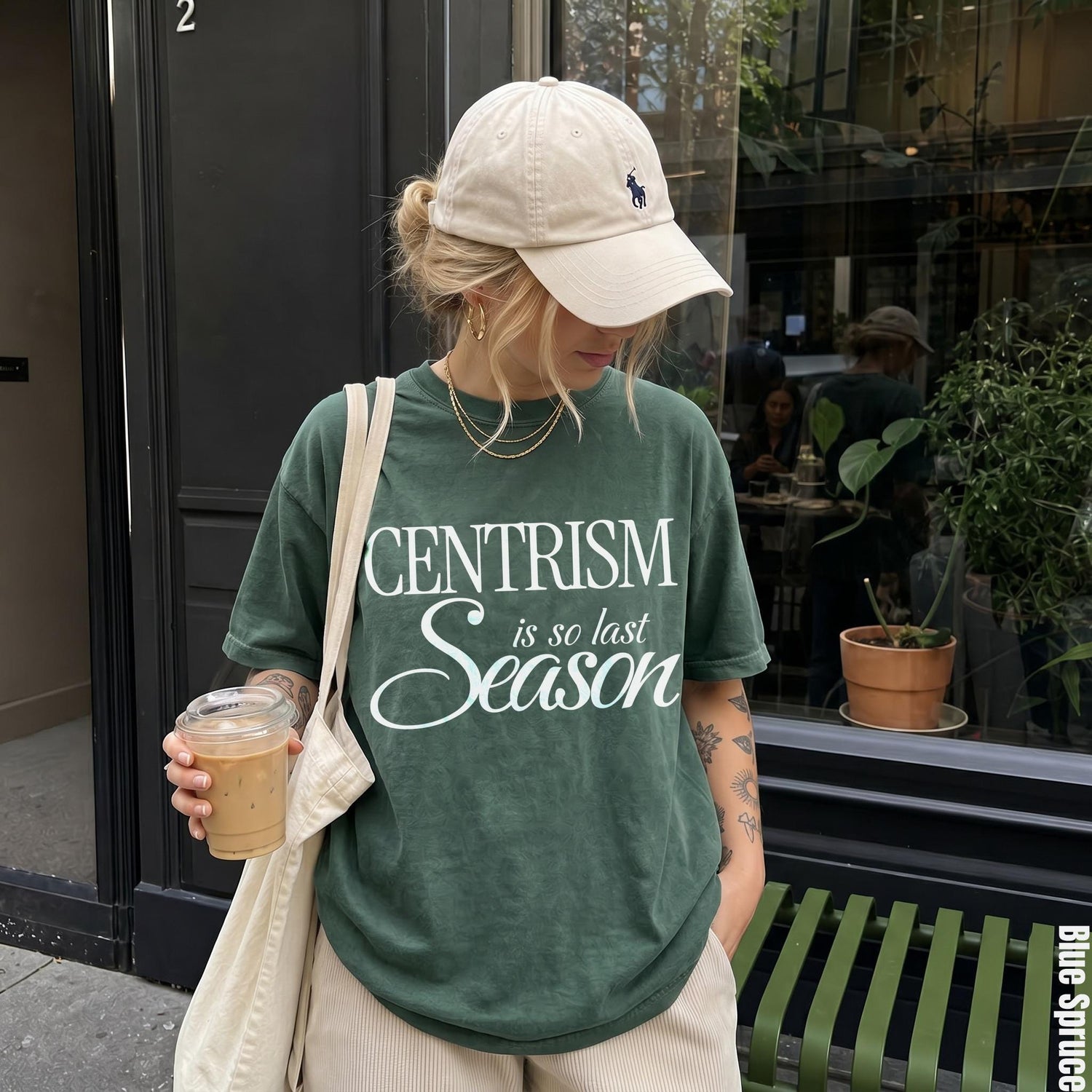 Green t-shirt with &amp;quot;CENTRISM is so last Season&amp;quot; text, holding iced coffee.