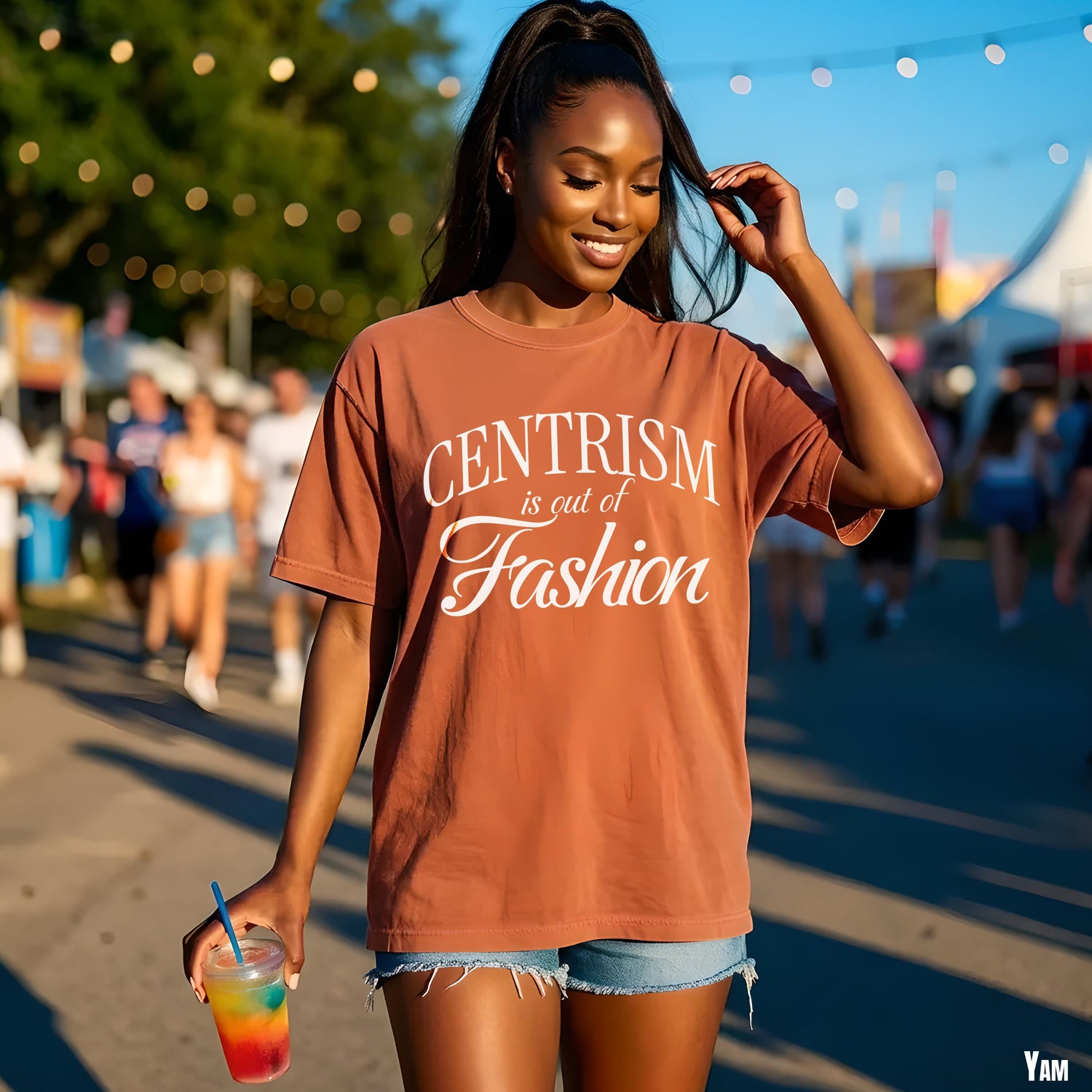 Woman in brown t-shirt with &amp;quot;Centrism is out of Fashion&amp;quot; text, holding colorful drink.