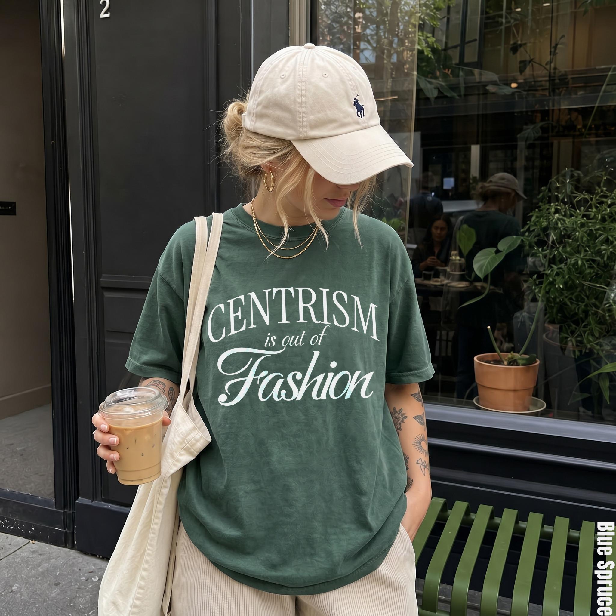 Green t-shirt with white text &amp;quot;CENTRISM is out of Fashion&amp;quot;, holding iced coffee.