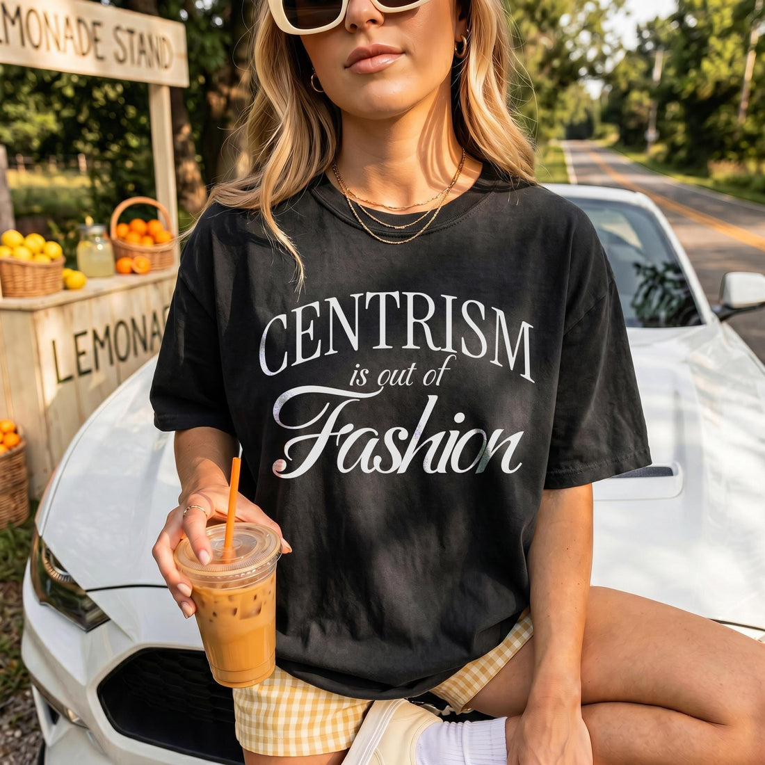 Black t-shirt with &amp;quot;CENTRISM is out of Fashion&amp;quot; text, holding iced coffee by lemonade stand.