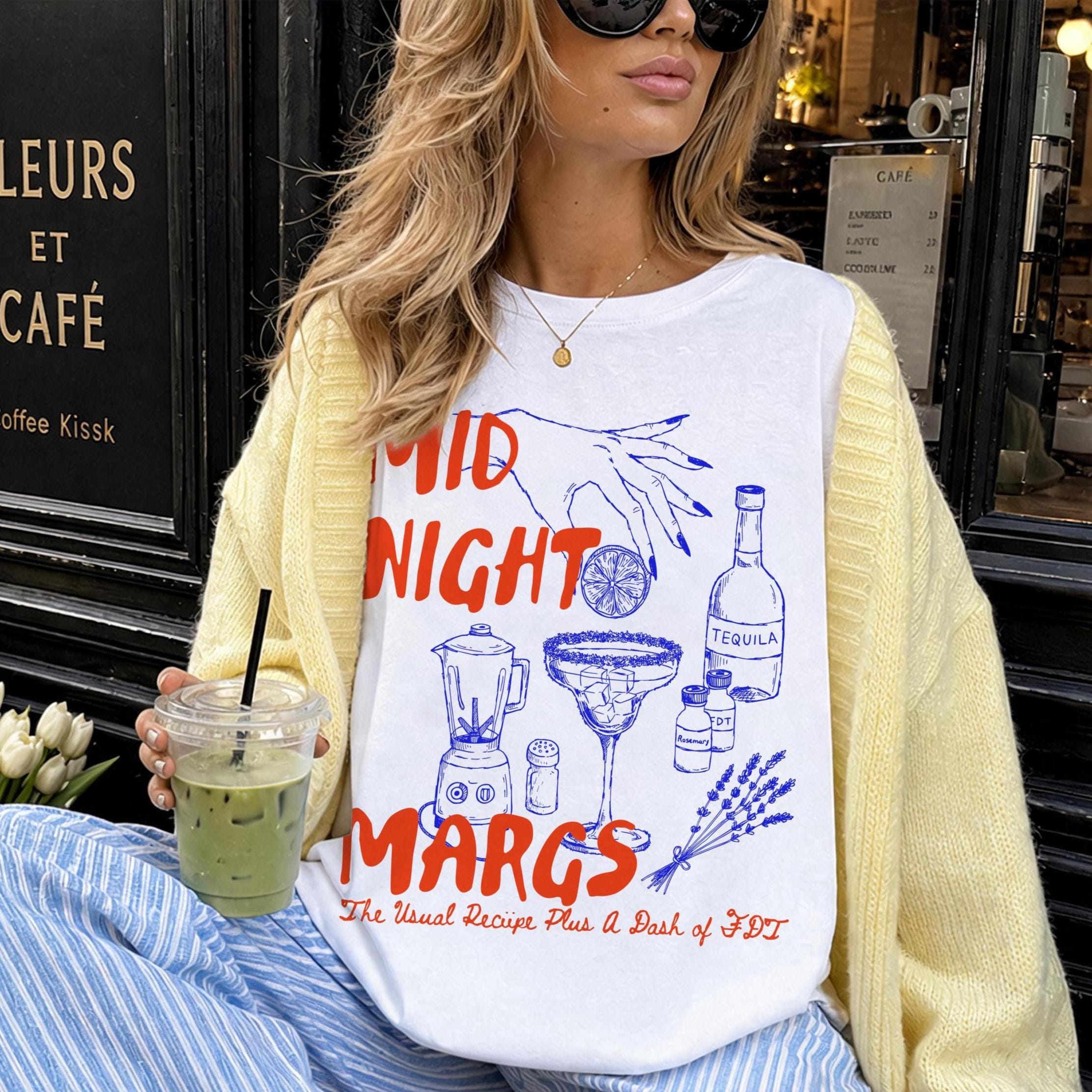 Woman in yellow cardigan and striped pants wears a white t-shirt with &amp;quot;Midnight Margs&amp;quot; and cocktail graphics.