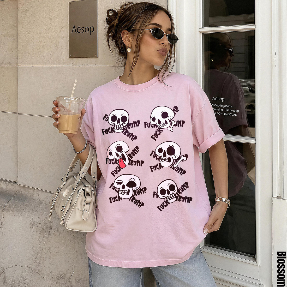 Pink t-shirt with &amp;quot;FUCK TRUMP&amp;quot; text and skull graphics, worn by a woman holding a drink.