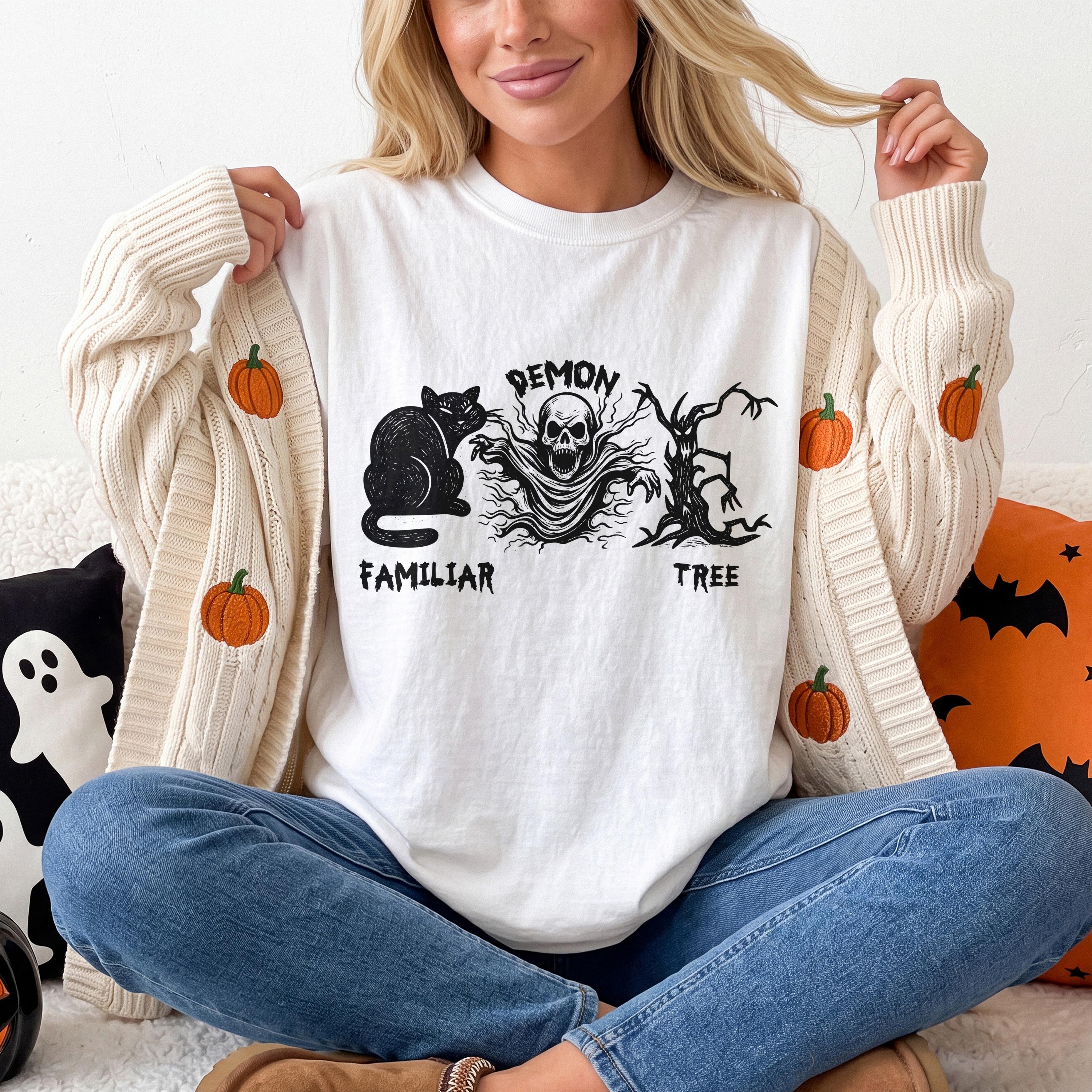 White t-shirt with black Halloween graphic: cat, demon skull, and tree.