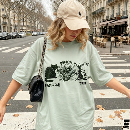 Light green t-shirt with &amp;quot;Demon Familiar Tree&amp;quot; graphic, woman wearing beige cap and black purse.