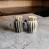 May include: Two gray ceramic cactus-shaped matchstick holders with white tips on the matches. The holders are on a white countertop.