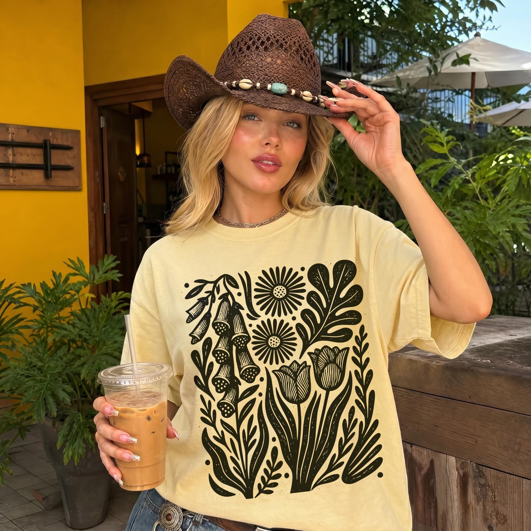Pale yellow t-shirt with black floral print, worn by a woman in a brown cowboy hat.