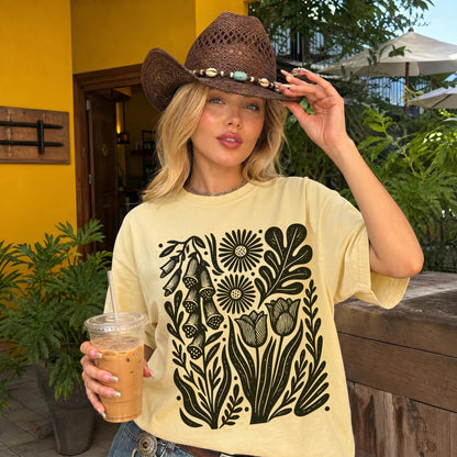 Pale yellow t-shirt with black floral print, worn by a woman in a brown cowboy hat.