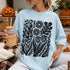 Light blue t-shirt with black floral and leaf print, held by a person with a drink.