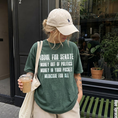 Green t-shirt with &amp;quot;Abdul for Senate&amp;quot; and political slogans.