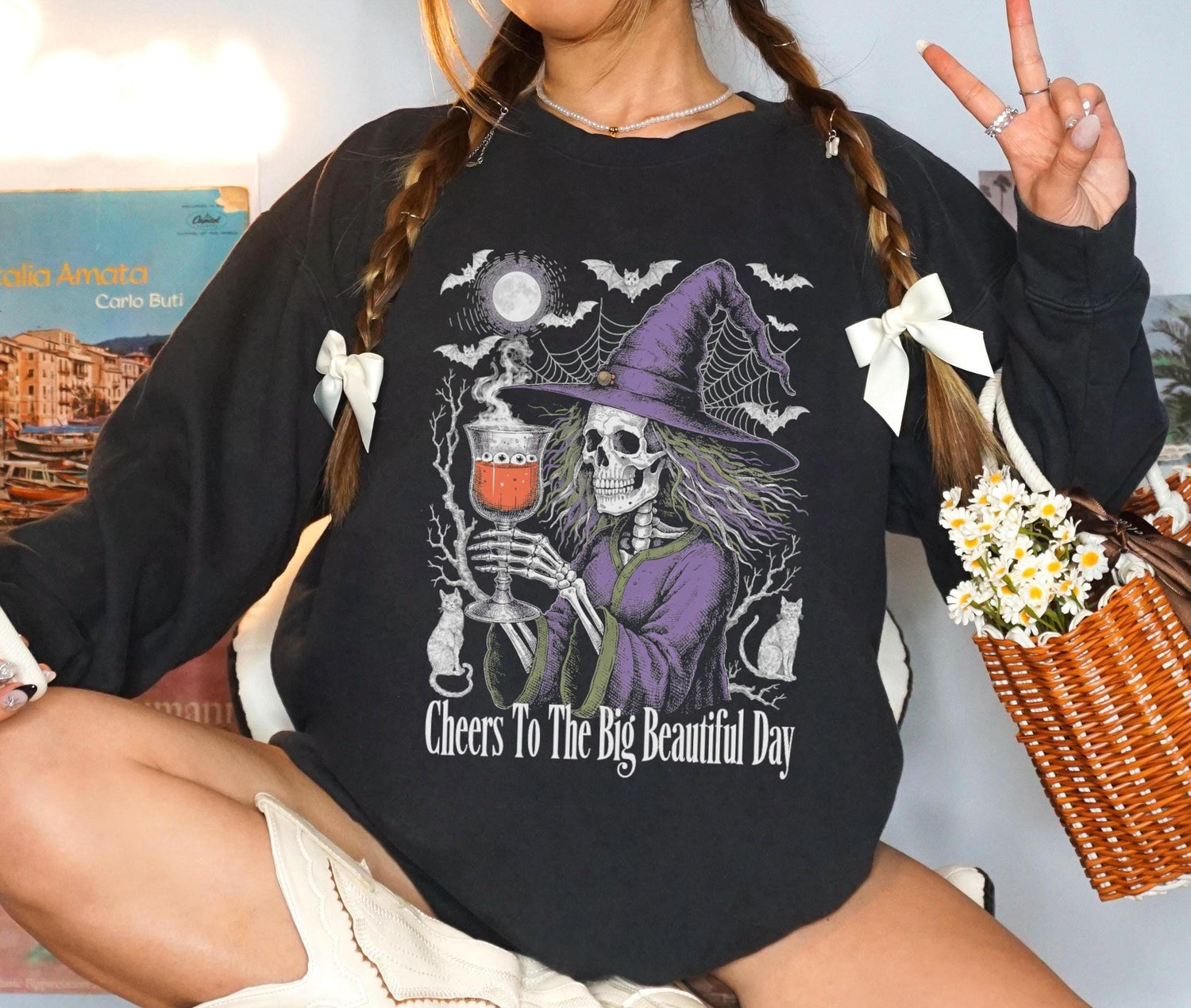 Black t-shirt with skeleton witch graphic and text &amp;quot;Cheers To The Big Beautiful Day&amp;quot;.