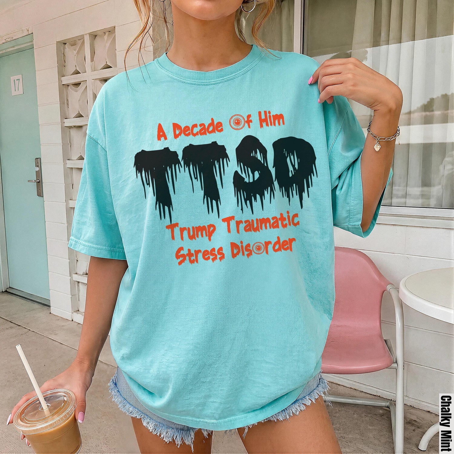 Aqua t-shirt with distressed black TTSD graphic and orange text &amp;quot;A Decade of Him&amp;quot; and &amp;quot;Trump Traumatic Stress Disorder&amp;quot;.