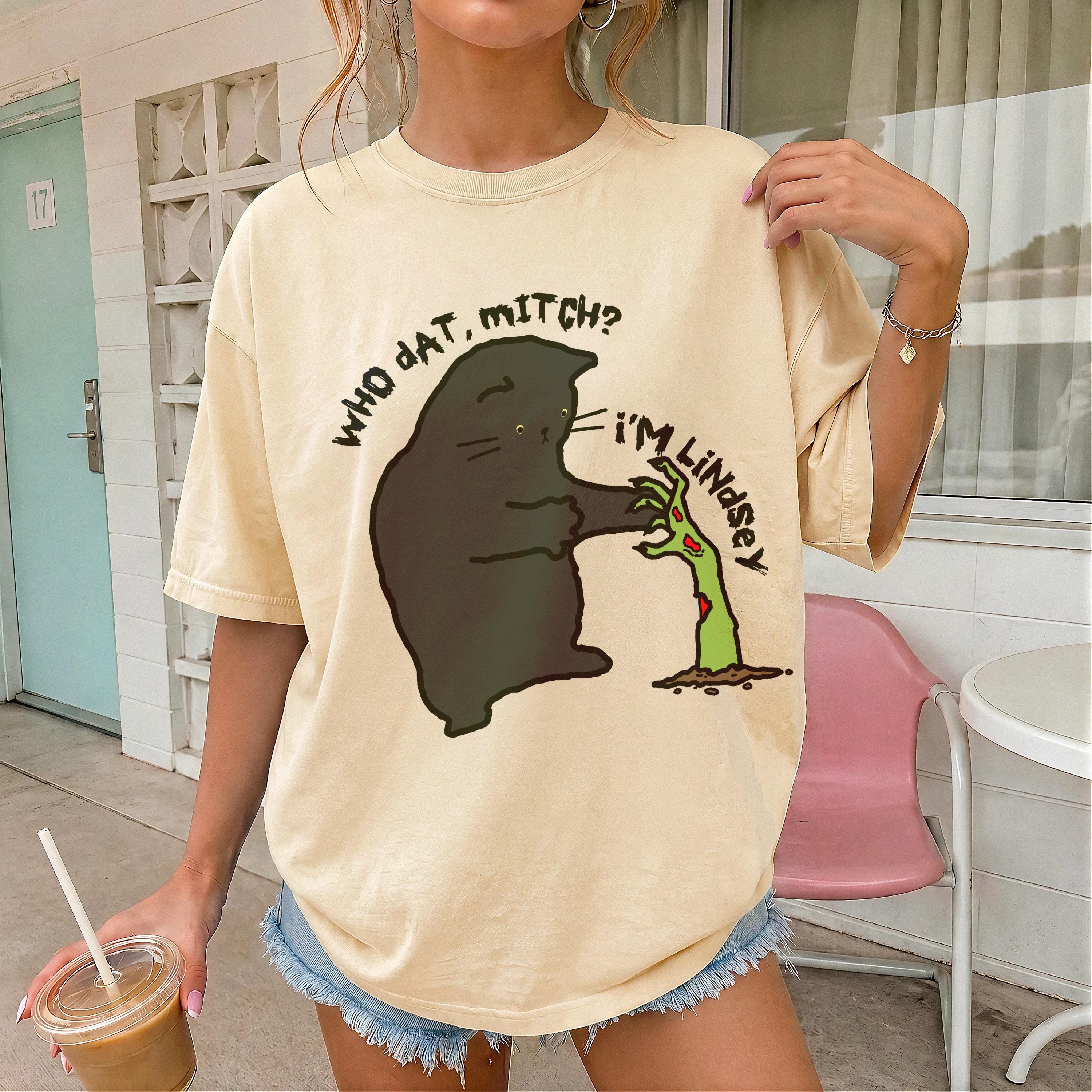 Black cat graphic on beige t-shirt with text &amp;quot;WHO DAT, MITCH?&amp;quot; and &amp;quot;I&amp;