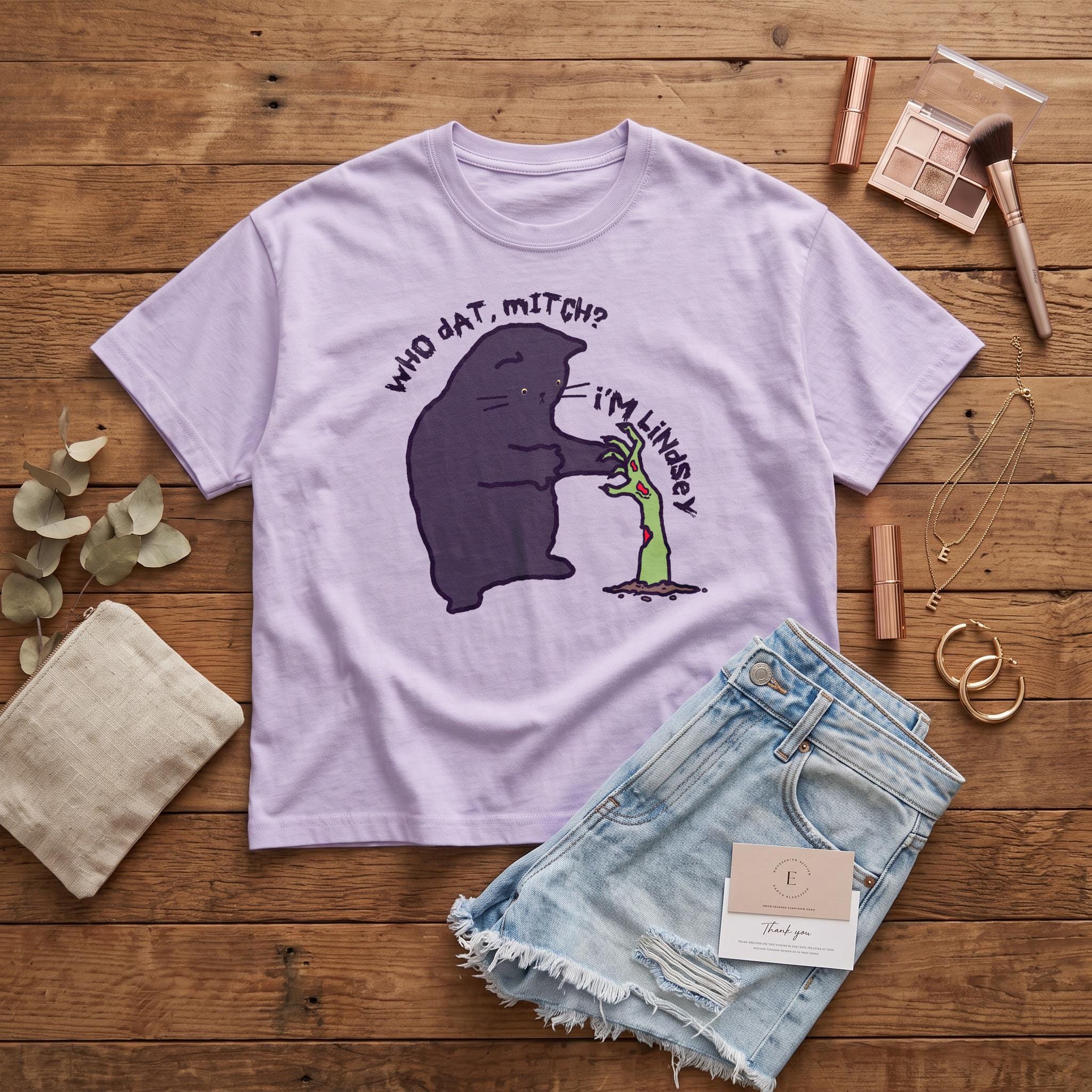 Lavender t-shirt with a black cat asking a zombie hand, &amp;quot;Who dat, Mitch?&amp;quot;