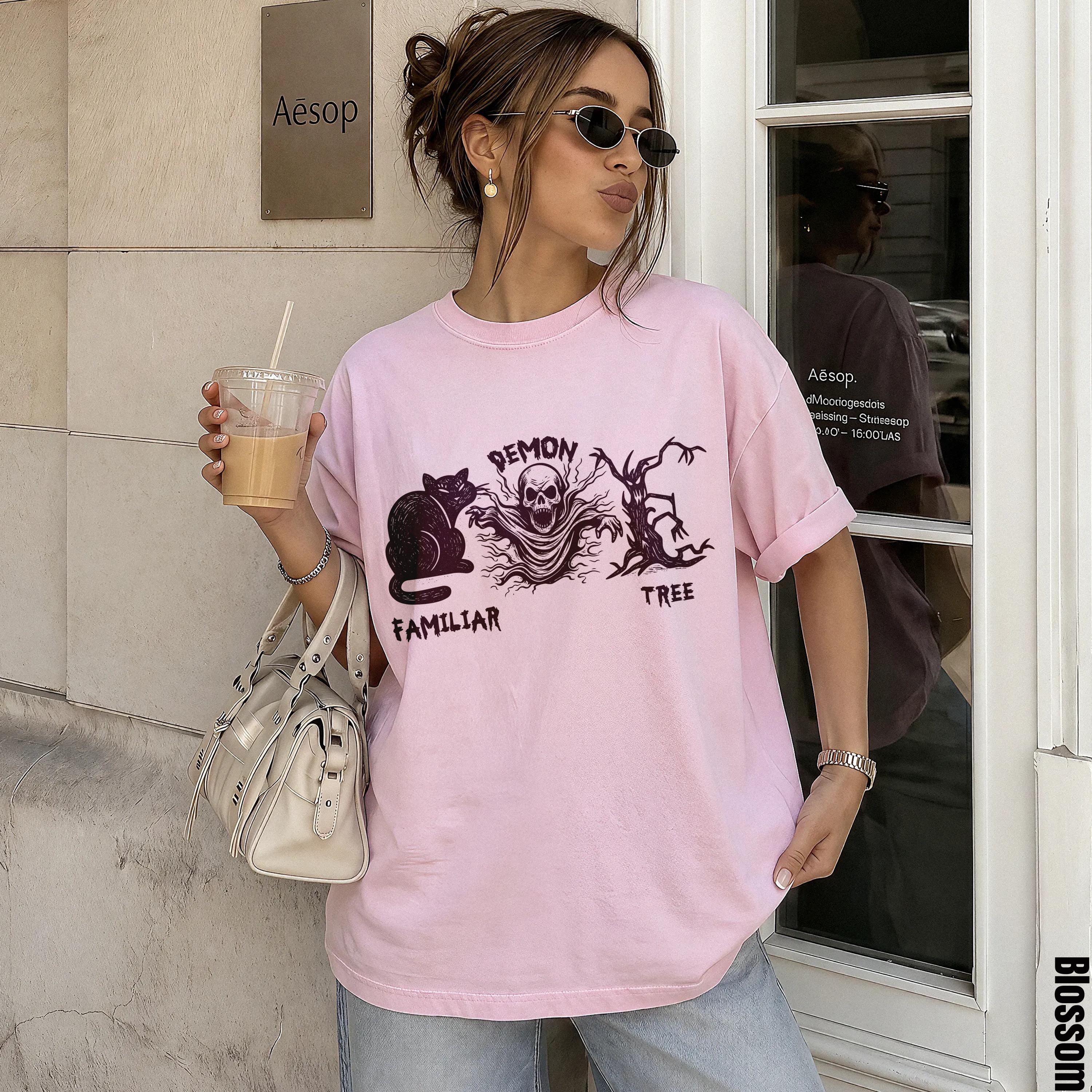 Pink t-shirt with black cat, skull, and tree graphic with text.