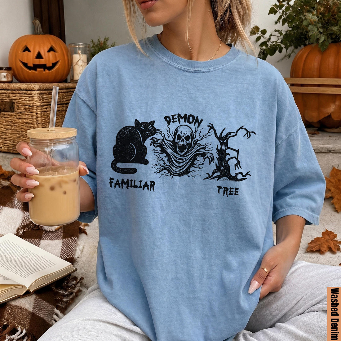 Light blue t-shirt with black cat, skull ghost, and dead tree Halloween graphic.