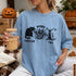 Light blue t-shirt with black cat, skull ghost, and dead tree Halloween graphic.