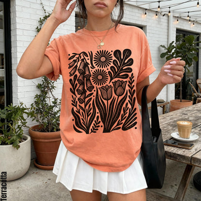 Peach t-shirt with black floral linocut design, white pleated skirt, black bag. &amp;quot;Terracotta&amp;quot; text.