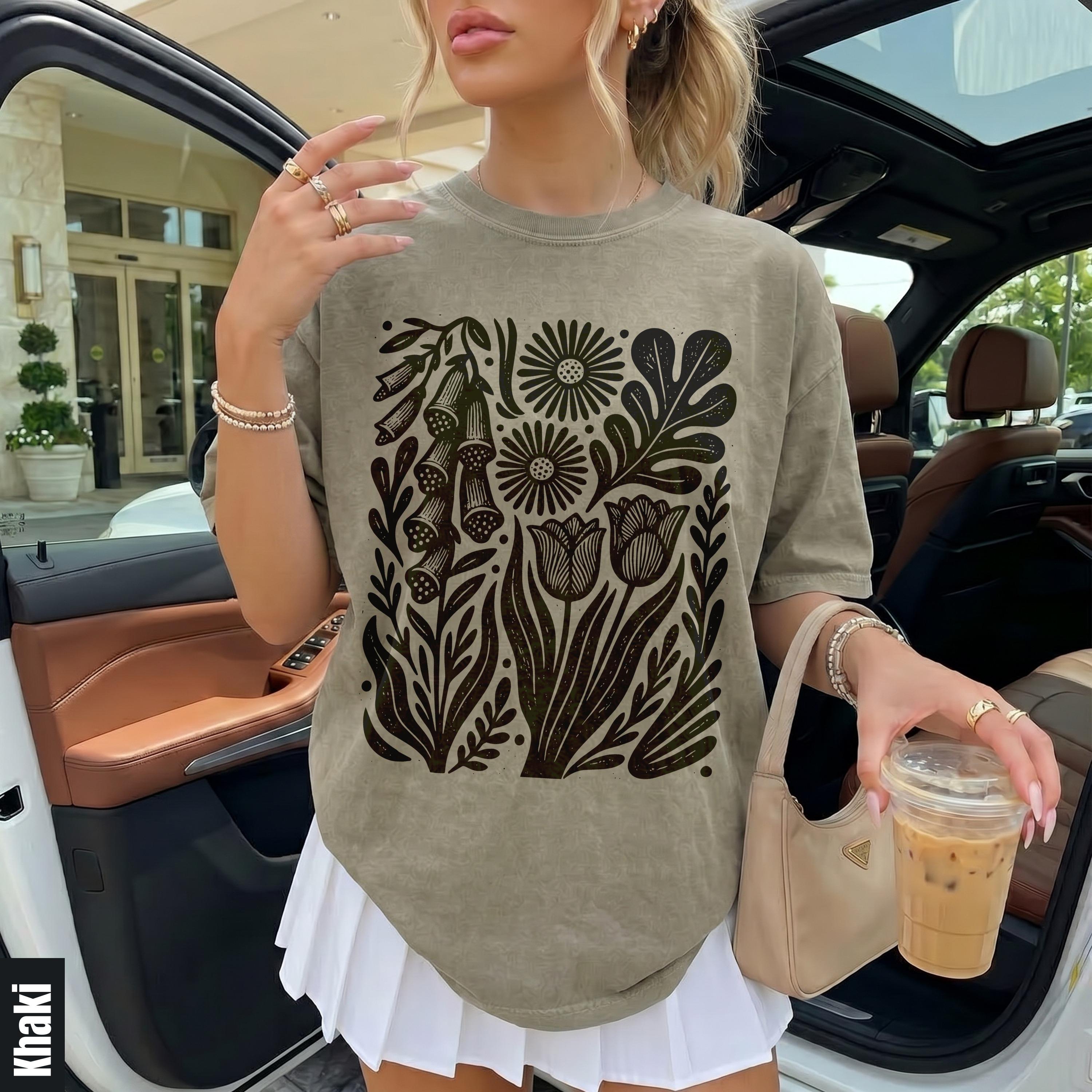Khaki t-shirt with dark floral print, white pleated skirt and a tan handbag.