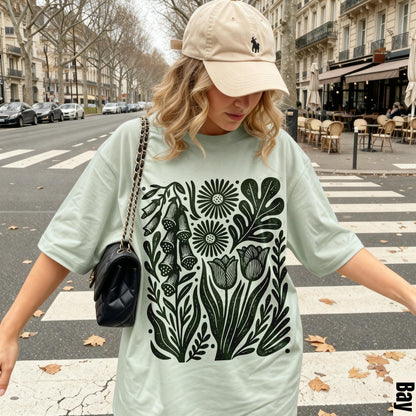 Woman wearing light green t-shirt with black floral print, standing on crosswalk.