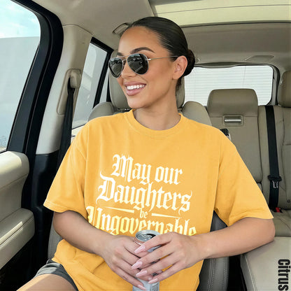 Woman in yellow shirt with &amp;quot;May our daughters be Ungovernable&amp;quot; text, holding can.