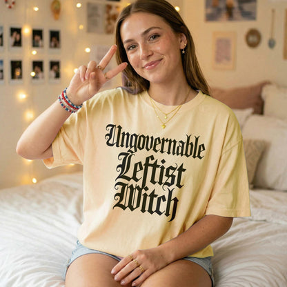 Young woman in a pale yellow t-shirt with black gothic text reading &amp;quot;Ungovernable Leftist Witch&amp;quot;.
