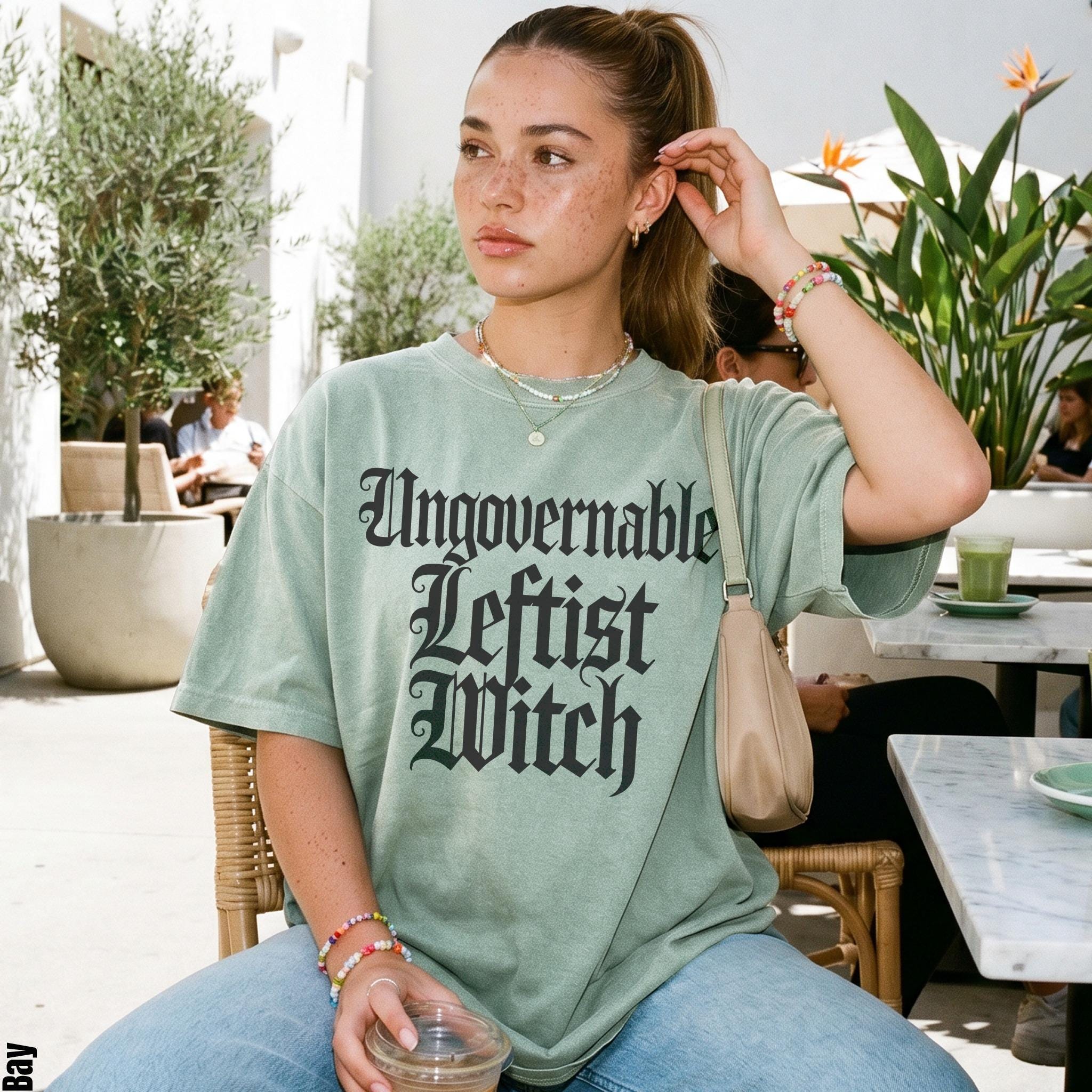 Light green t-shirt with &amp;quot;Ungovernable Leftist Witch&amp;quot; text in black gothic font.