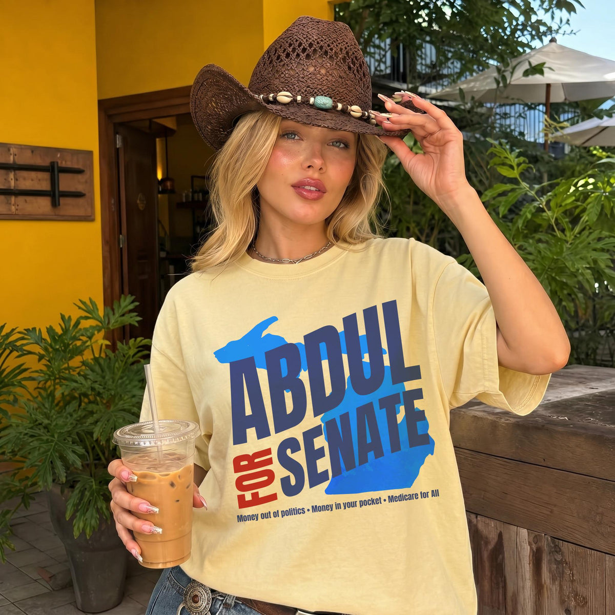 Woman in yellow t-shirt with &amp;quot;ABDUL FOR SENATE&amp;quot; text and political slogans.