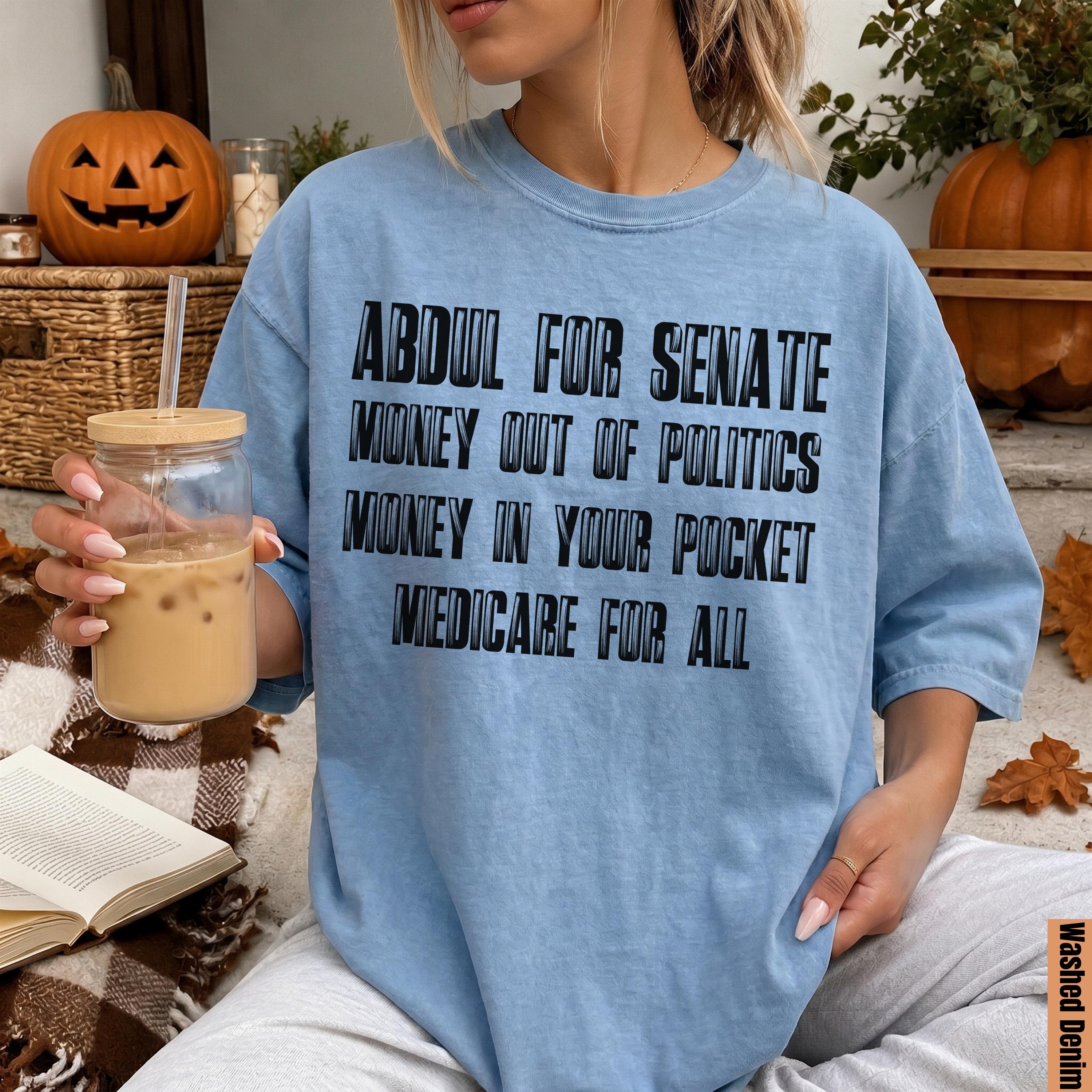 Light blue t-shirt with text: Abdul for Senate, Money out of politics, Money in your pocket, Medicare for all.