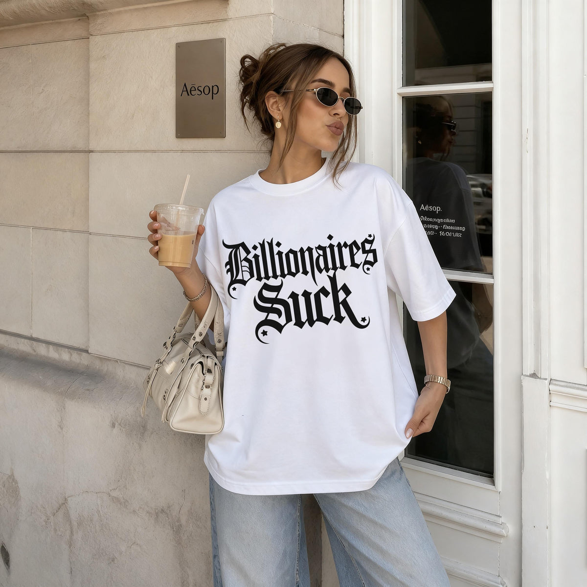 White t-shirt with &amp;quot;Billionaires Suck&amp;quot; text, worn by a woman holding a drink.